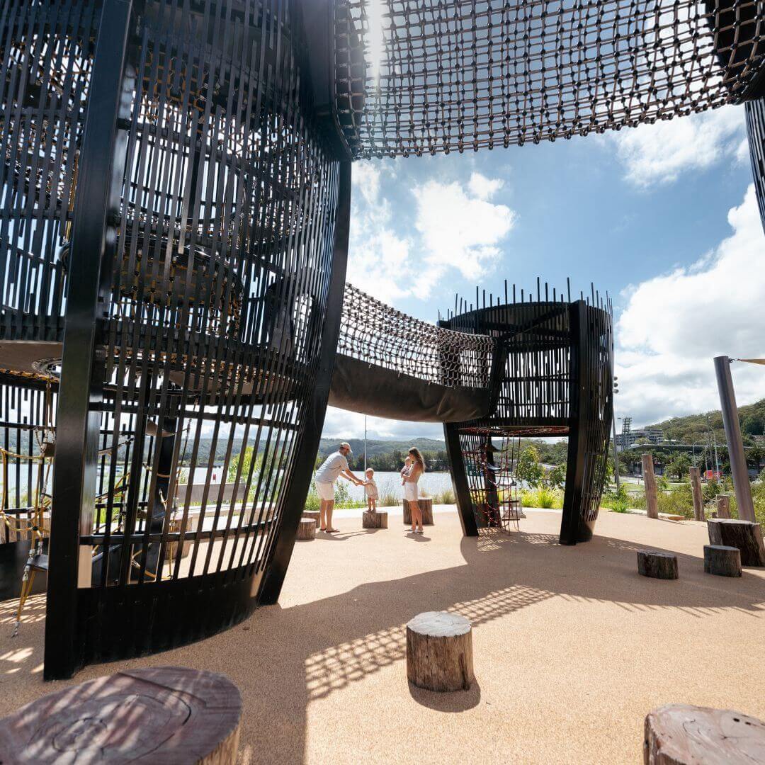 A family playing with their child surrounded by a large playground structure